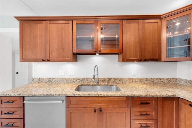 kitchen with stainless steel dishwasher, light stone countertops, and sink