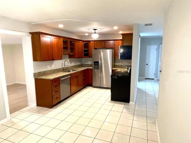 kitchen featuring light stone countertops, sink, light tile patterned flooring, and stainless steel appliances