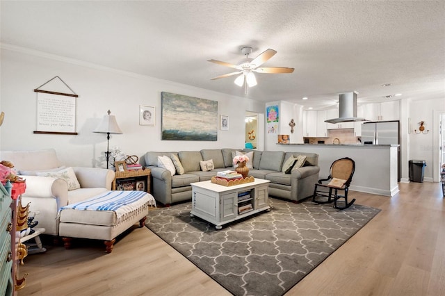 living room with hardwood / wood-style floors, ceiling fan, ornamental molding, and a textured ceiling