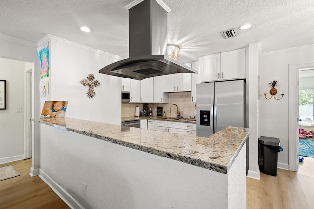 kitchen with white cabinetry, kitchen peninsula, island exhaust hood, appliances with stainless steel finishes, and light hardwood / wood-style floors