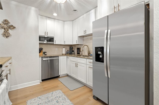 kitchen with stainless steel appliances, light wood-type flooring, white cabinets, and tasteful backsplash