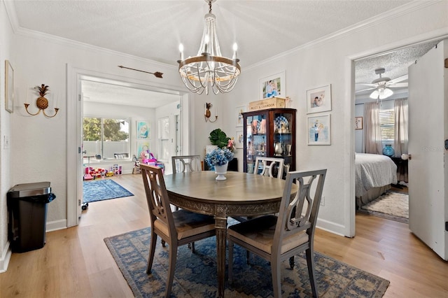 dining space featuring ceiling fan with notable chandelier, a textured ceiling, light hardwood / wood-style flooring, and ornamental molding