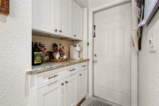 bar with light stone counters and white cabinetry