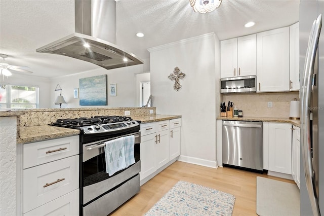 kitchen with light hardwood / wood-style flooring, appliances with stainless steel finishes, light stone countertops, ceiling fan, and island range hood