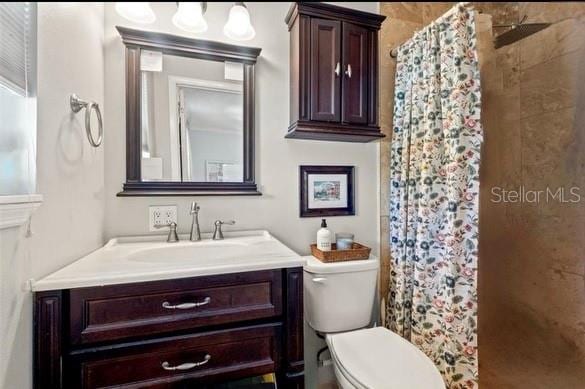 bathroom featuring vanity, toilet, and walk in shower