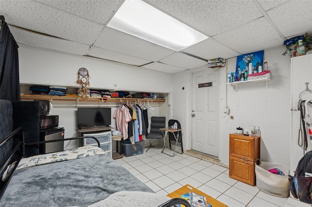 bedroom with a paneled ceiling, light tile patterned floors, and a closet