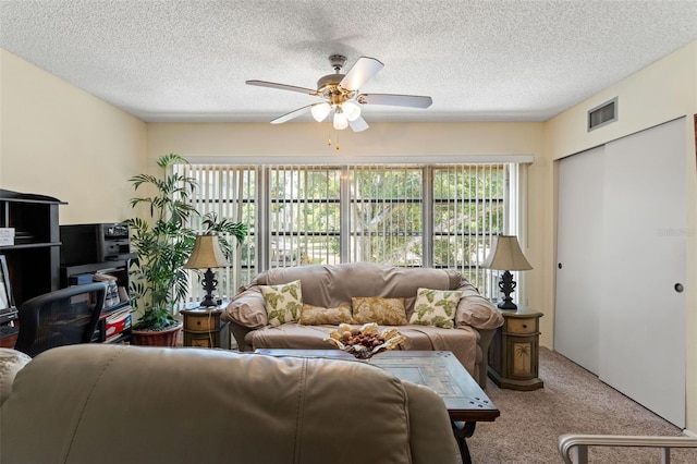 living room with ceiling fan, a textured ceiling, and carpet floors