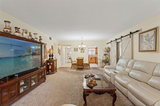 carpeted living room with a barn door, a textured ceiling, and a chandelier