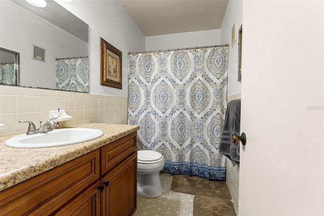 bathroom with backsplash, toilet, vanity, tile patterned floors, and tile walls