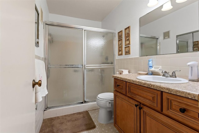 bathroom with backsplash, toilet, vanity, tile patterned floors, and a shower with shower door