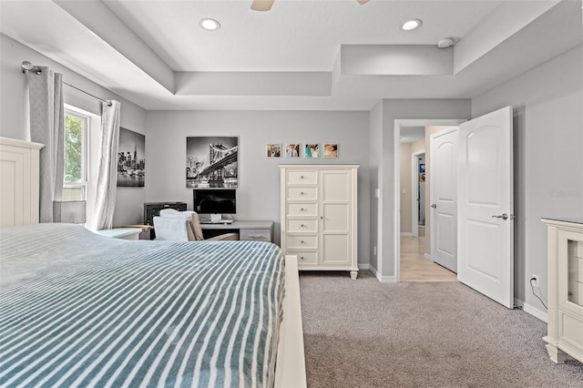 bedroom with a tray ceiling and light colored carpet