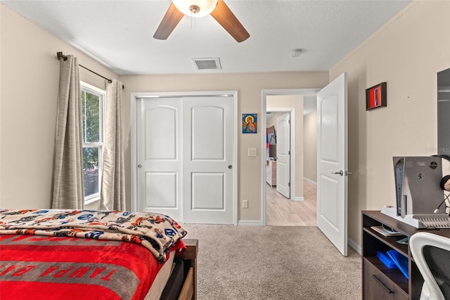 bedroom featuring light colored carpet, ceiling fan, and a closet