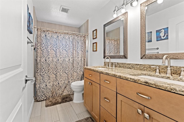 bathroom with a shower with shower curtain, tile patterned floors, toilet, vanity, and a textured ceiling