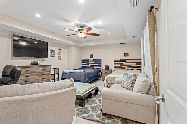 living room featuring a raised ceiling, ceiling fan, and light hardwood / wood-style floors