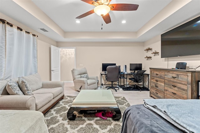 bedroom with ceiling fan, hardwood / wood-style flooring, and a raised ceiling