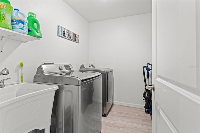 laundry room featuring light hardwood / wood-style flooring, washing machine and dryer, and sink