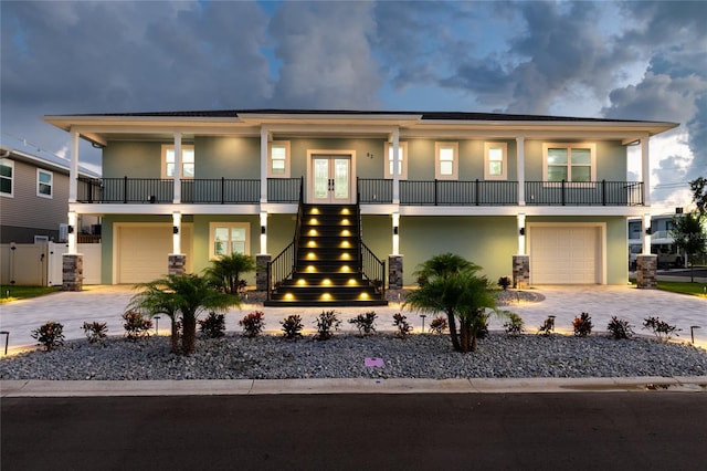 view of front of home featuring stairway, an attached garage, decorative driveway, french doors, and stucco siding