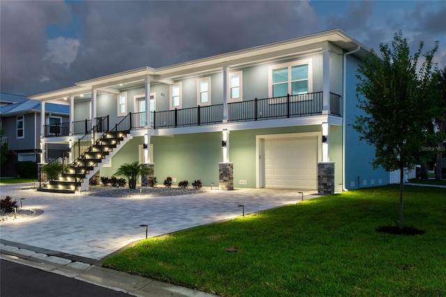 townhome / multi-family property with stairs, decorative driveway, a front lawn, and stucco siding