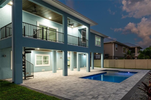 back house at dusk with a fenced in pool, ceiling fan, and a patio