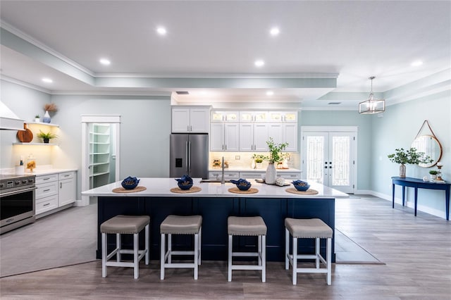 kitchen featuring a breakfast bar, a large island with sink, stainless steel appliances, and white cabinetry