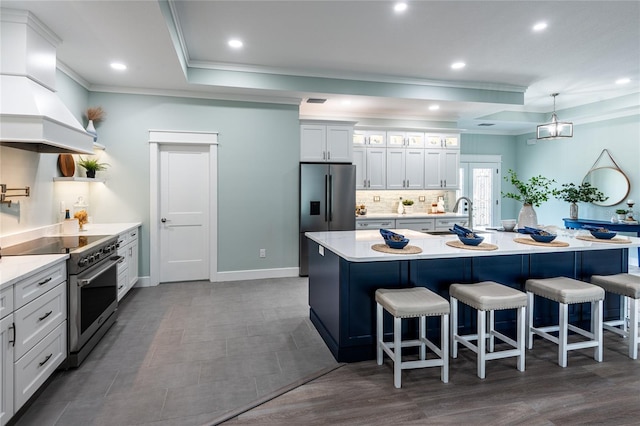 kitchen featuring tasteful backsplash, a raised ceiling, appliances with stainless steel finishes, a breakfast bar, and light countertops