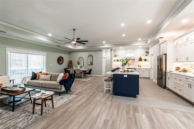 living room with baseboards, a tray ceiling, recessed lighting, and crown molding