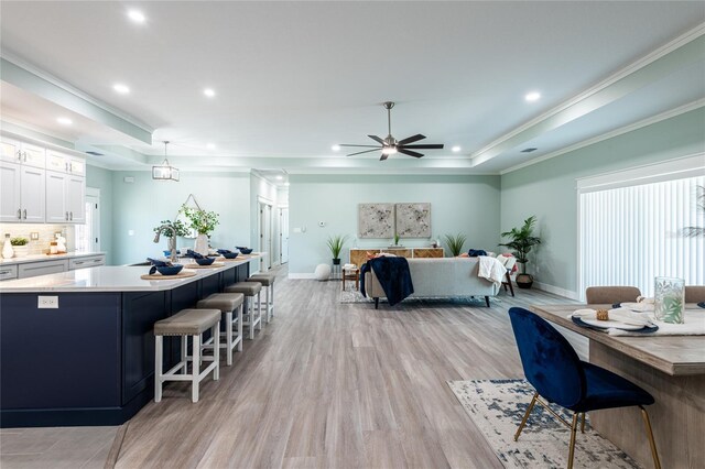 interior space featuring backsplash, light hardwood / wood-style flooring, white cabinetry, and ornamental molding