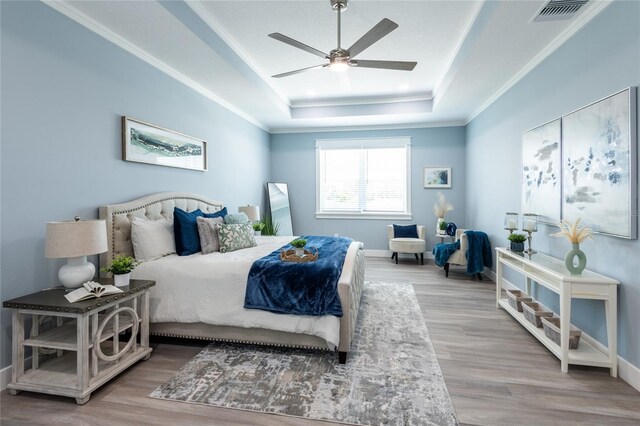 bedroom with a tray ceiling, ceiling fan, crown molding, and hardwood / wood-style flooring