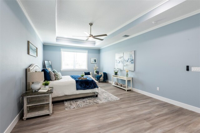 bedroom with a raised ceiling, ceiling fan, light hardwood / wood-style flooring, and ornamental molding