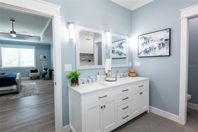 bathroom featuring ceiling fan, toilet, hardwood / wood-style flooring, vanity, and ornamental molding