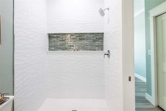 bathroom with hardwood / wood-style floors and a tile shower