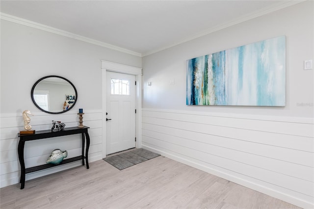 foyer entrance with ornamental molding, wainscoting, and wood finished floors