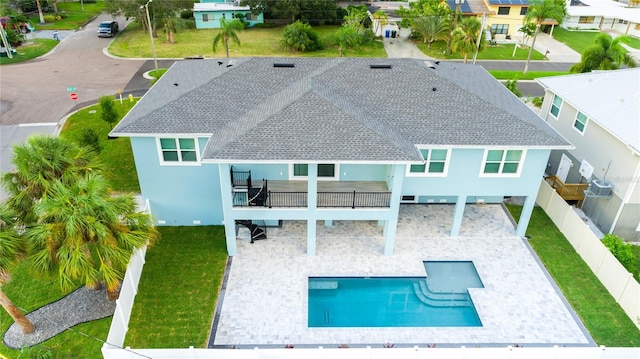 rear view of property featuring a patio, a fenced backyard, a balcony, driveway, and a carport