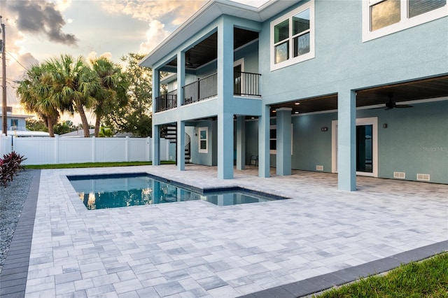 pool at dusk featuring a patio area and ceiling fan