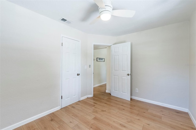 empty room featuring visible vents, ceiling fan, light wood-type flooring, and baseboards