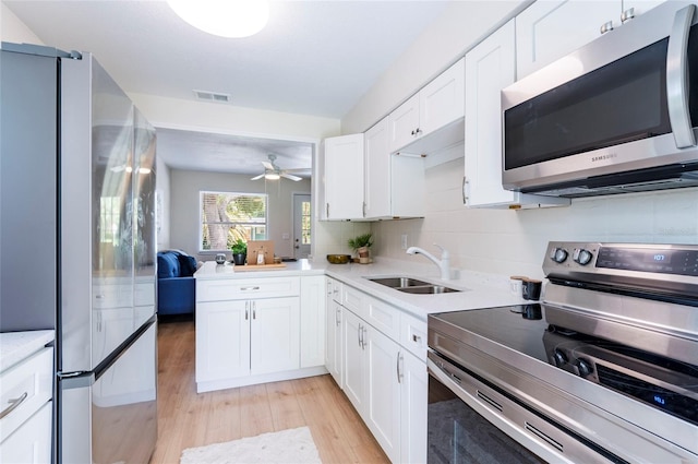 kitchen featuring visible vents, a sink, light wood-style floors, appliances with stainless steel finishes, and white cabinets