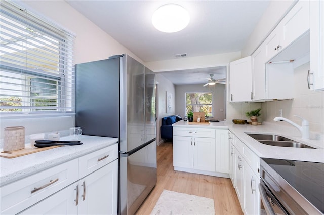 kitchen with visible vents, light wood-style flooring, stainless steel appliances, a sink, and white cabinets