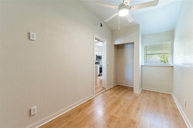 spare room featuring ceiling fan, visible vents, baseboards, and light wood-style flooring