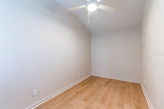 empty room featuring light wood-style flooring, a ceiling fan, baseboards, and vaulted ceiling