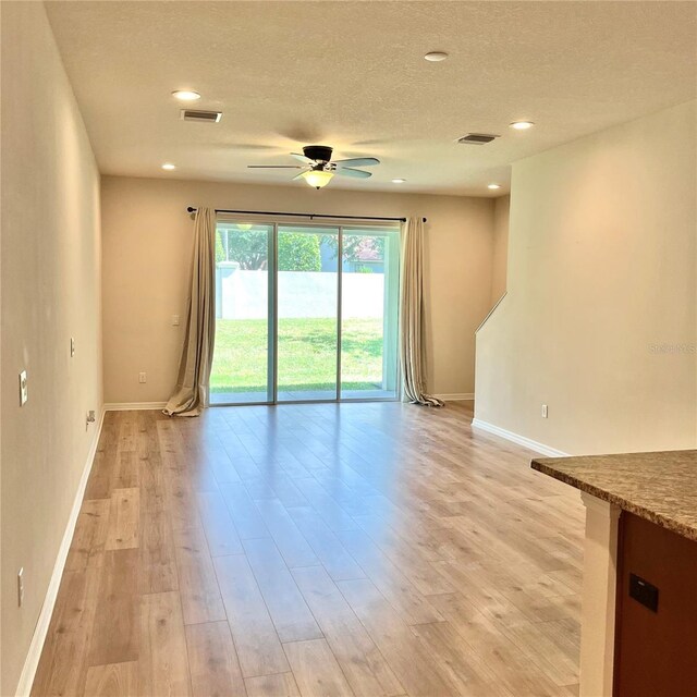 empty room featuring ceiling fan, light wood-type flooring, and a textured ceiling