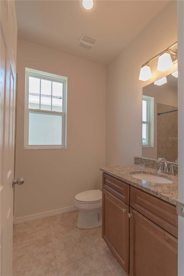 bathroom with a wealth of natural light, toilet, vanity, and tile patterned floors