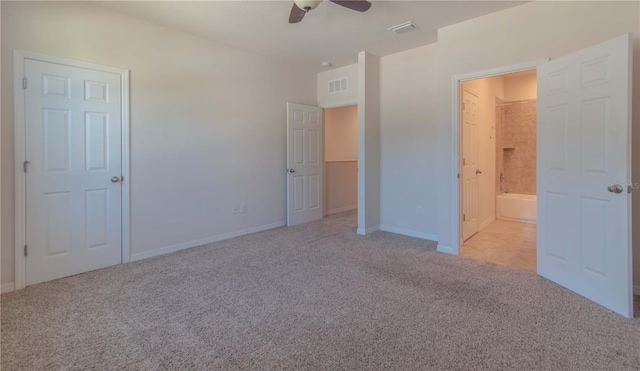 unfurnished bedroom with ceiling fan, light colored carpet, and ensuite bathroom