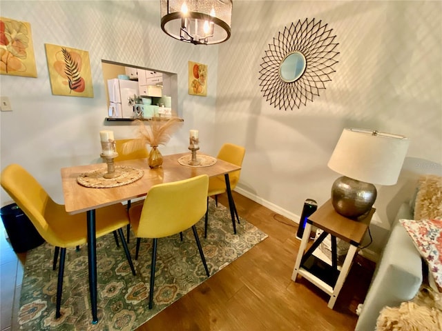 dining space with hardwood / wood-style floors and an inviting chandelier