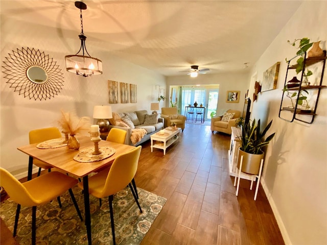 dining space with ceiling fan with notable chandelier and wood-type flooring