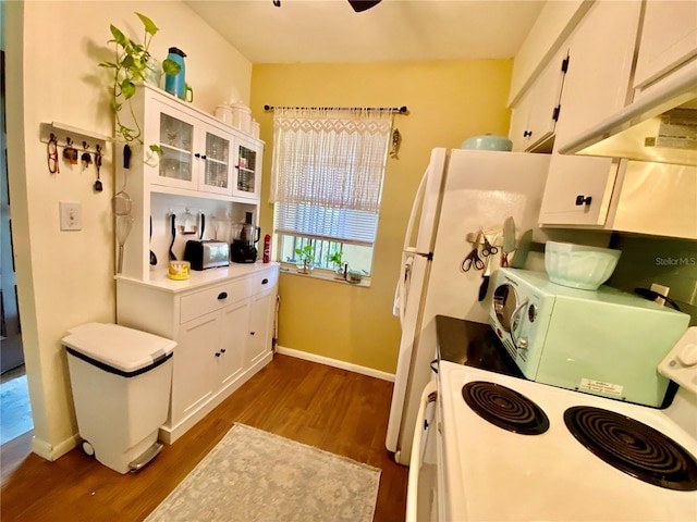 kitchen with dark hardwood / wood-style flooring, white cabinets, premium range hood, and range