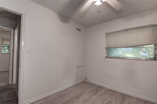 empty room featuring ceiling fan, plenty of natural light, hardwood / wood-style floors, and a textured ceiling