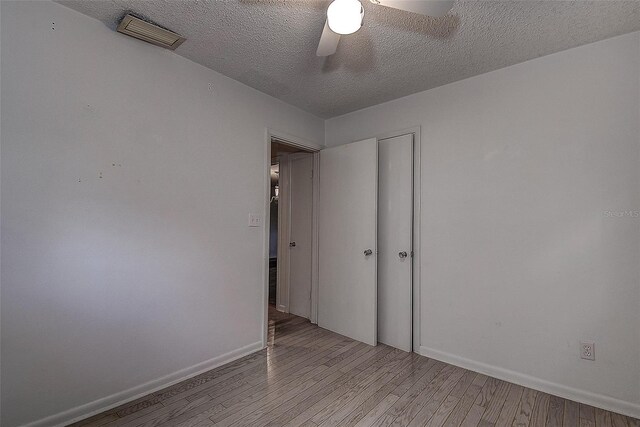 unfurnished bedroom featuring light wood-type flooring, ceiling fan, and a textured ceiling