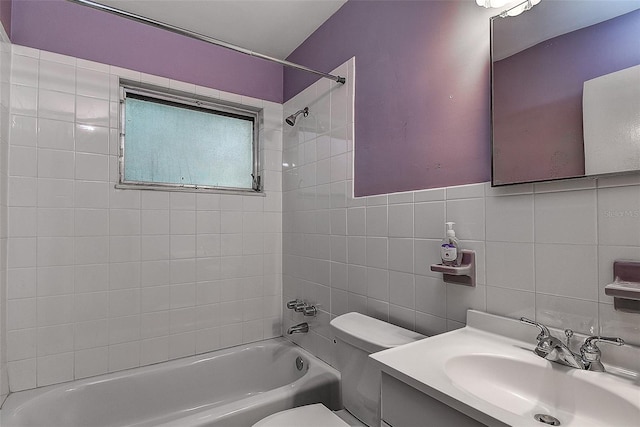 full bathroom with tile walls, tiled shower / bath combo, vanity, and toilet