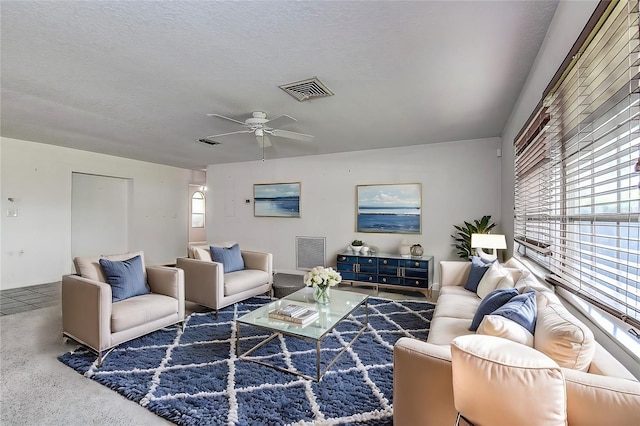 living room featuring dark colored carpet, ceiling fan, and a textured ceiling