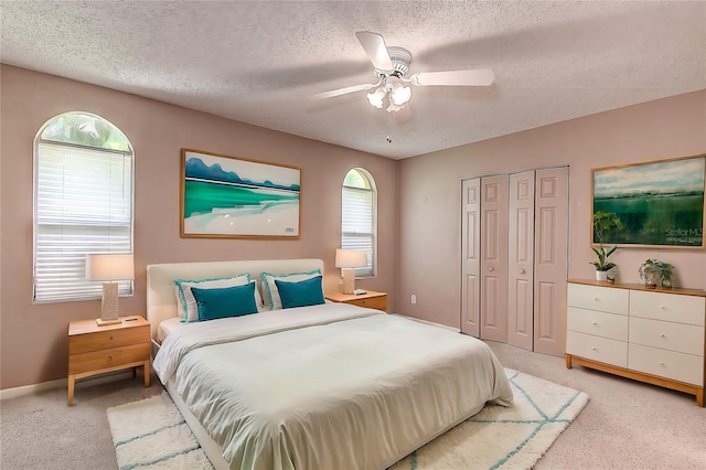 carpeted bedroom with ceiling fan, a textured ceiling, and a closet